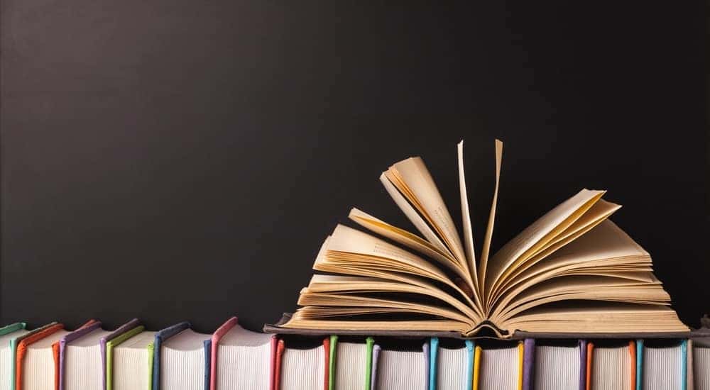 Open book on top of many books standing up straight