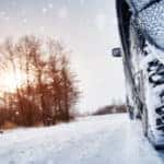 Close-up of snow tires driving down a snowy road