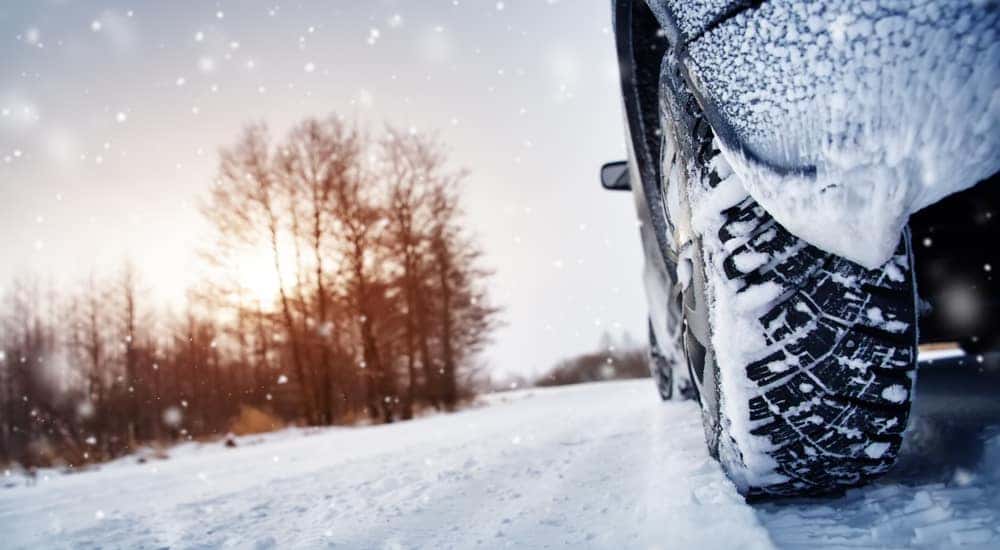 Close-up of snow tires driving down a snowy road