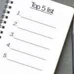 Notebook with a "Top 5 List" drawn on it sitting on a grey table next to a black pen
