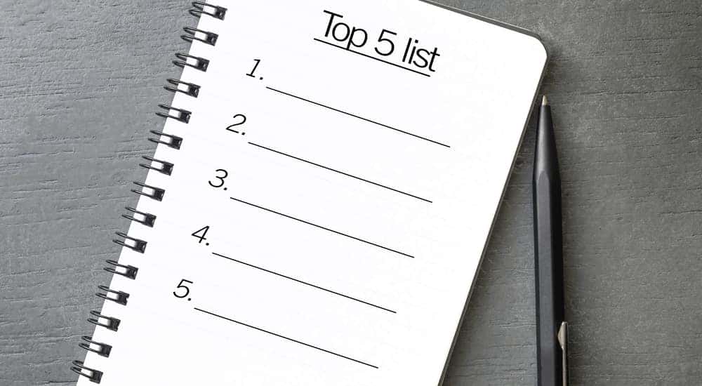 Notebook with a "Top 5 List" drawn on it sitting on a grey table next to a black pen