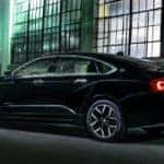 Black 2016 Chevy Impala parked next to a building with large windows