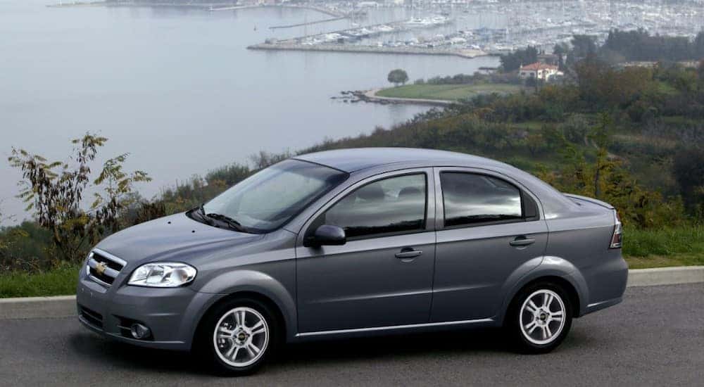 Grey 2011 Chevrolet Aveo sedan parked in front of a marina