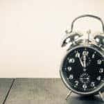 Retro alarm clock on a table in front of a vintage background