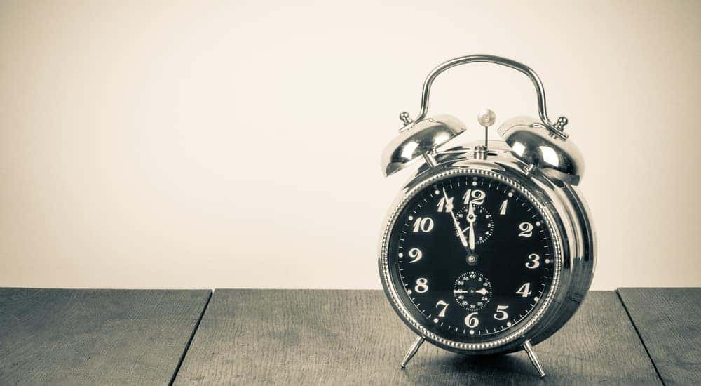 Retro alarm clock on a table in front of a vintage background