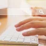 Transparent search bar in front of hands typing on a wireless keyboard