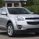 Silver 2011 Chevrolet Equinox SUV parked in front of trees and a stone building