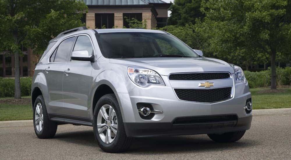 Silver 2011 Chevrolet Equinox SUV parked in front of trees and a stone building