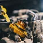 Synthetic oil being poured into the oil tank under the open hood of a vehicle