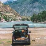 Vehicle with a full, open trunk parked in front of mountains in the sunlight