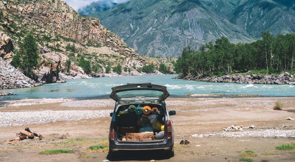 Vehicle with a full, open trunk parked in front of mountains in the sunlight
