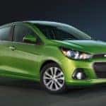 Green 2016 Chevrolet Spark hatchback parked in an all-black room