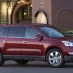 Red 2009 Chevrolet Traverse SUV parked in front of a brick building