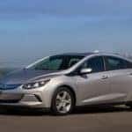 Silver 2017 Chevrolet Volt sedan parked on the side of the road in front of a city skyline