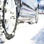 Tires driving through the snow toward tall mountains