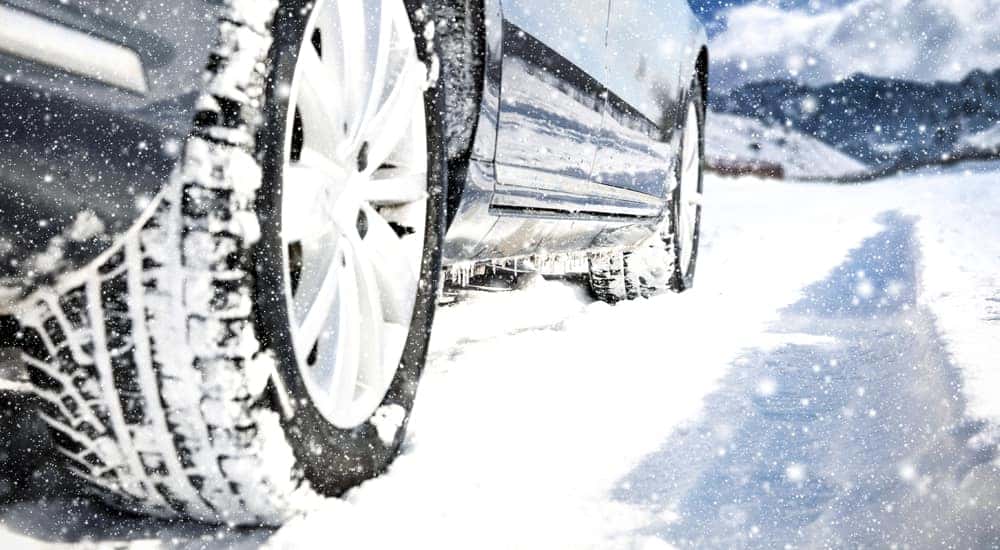 Tires driving through the snow toward tall mountains