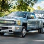 Grey 2017 Chevrolet Silverado 3500HD truck pulling a trailer by trees and grass