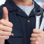 Auto service mechanic holding wrenches in one hand and giving a thumbs up with the other