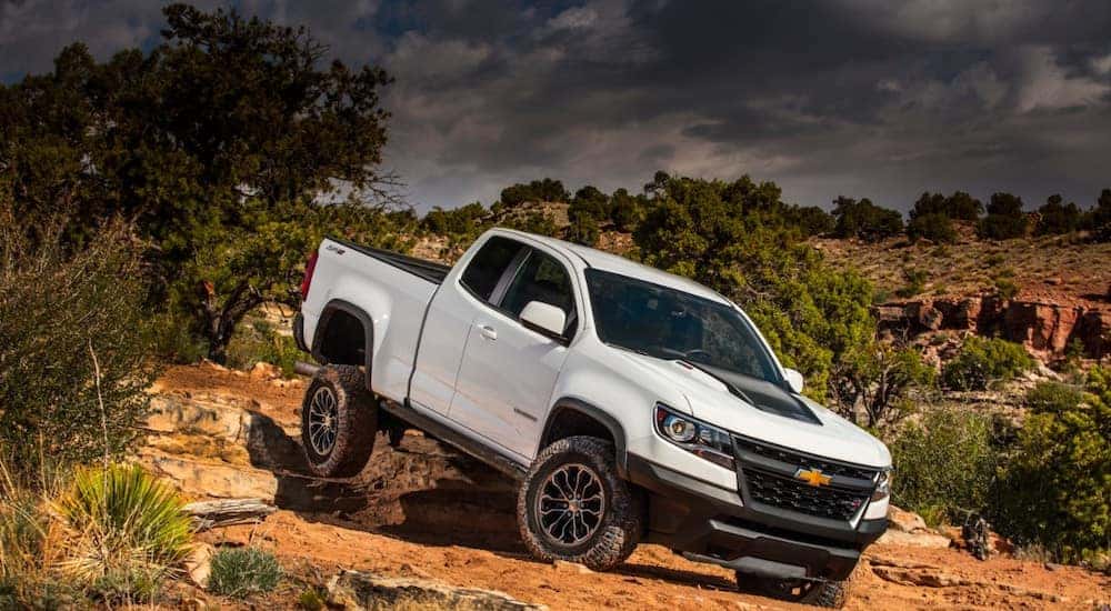 White 2017 Chevrolet Colorado pickup truck driving down rocky dirt terrain