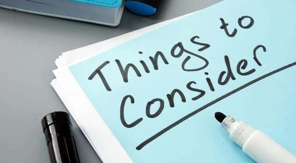 Black marker sitting on top of a blue paper with the words "Things to Consider" written on it in black ink