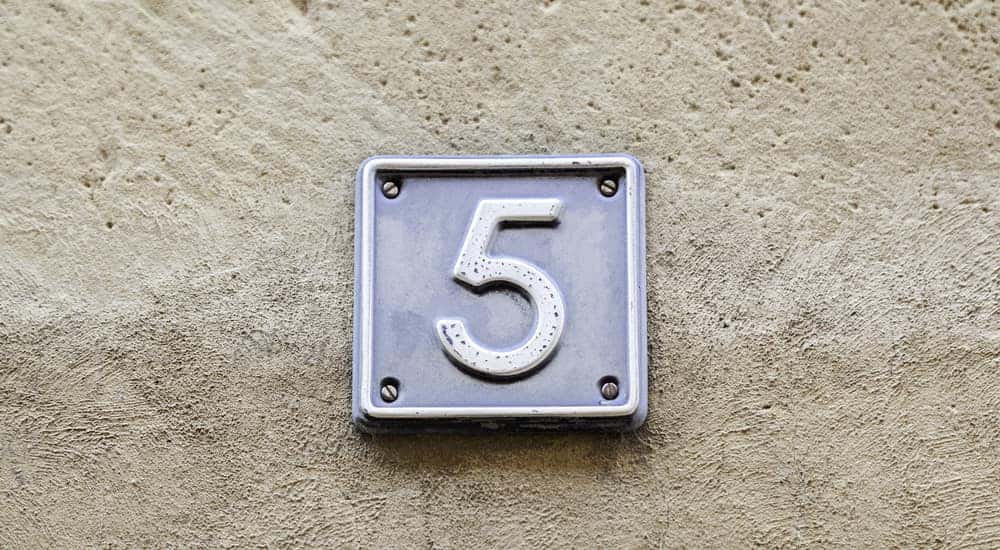 Silver plaque with the number five on it against a tan cement background