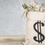 Brown sack with a money symbol of it filled with cash