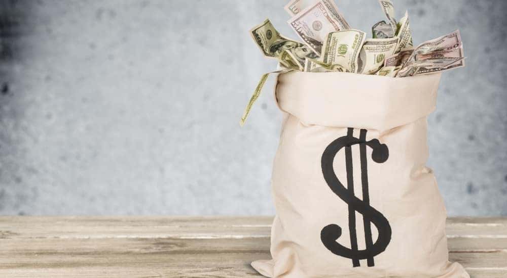Brown sack with a money symbol of it filled with cash