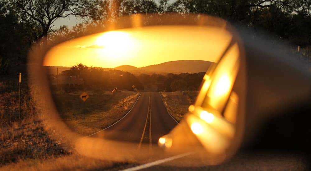 Long road and a sunset in the driver's side mirror of a vehicle