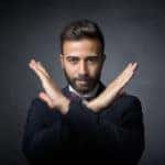 Man in a black sweater making an X with his arms