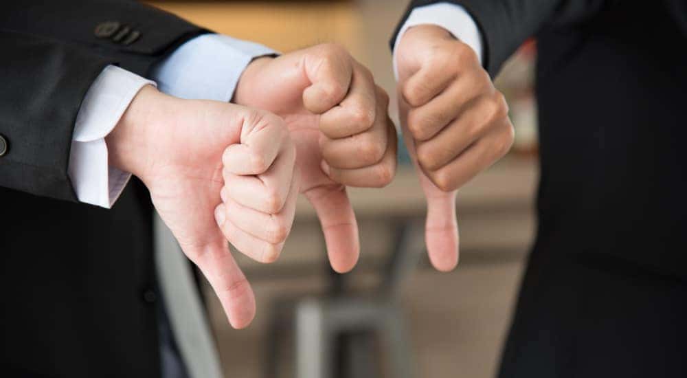 Three businessmen giving thumbs down