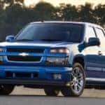 Blue 2012 Chevrolet Colorado pickup truck parked on pavement in front of trees
