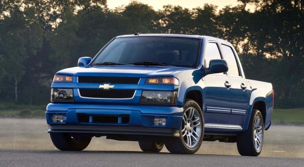 Blue 2012 Chevrolet Colorado pickup truck parked on pavement in front of trees