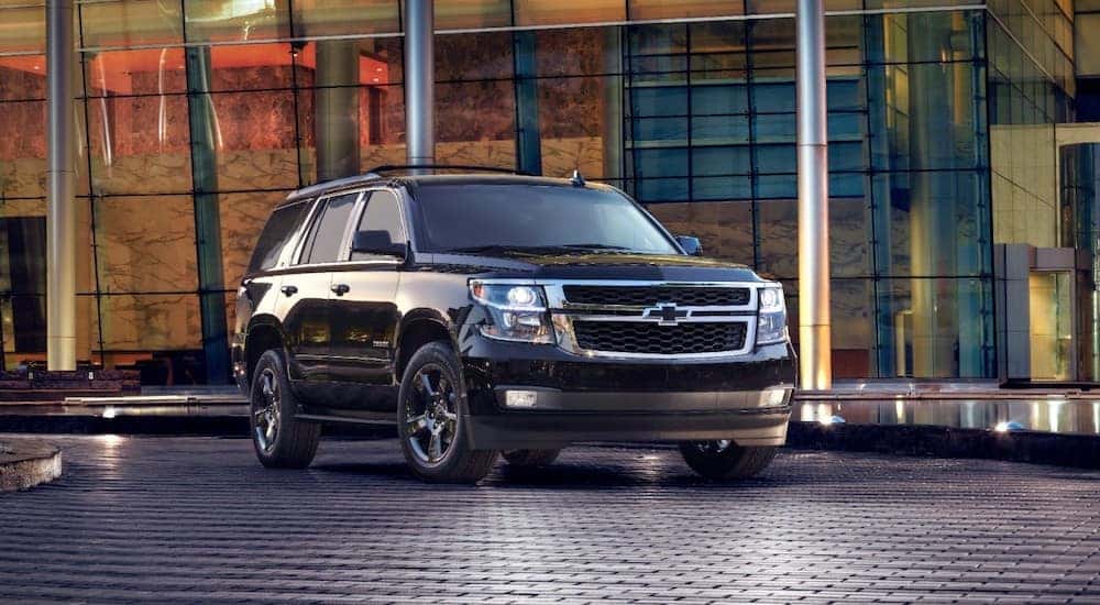 Black 2017 Chevrolet Tahoe SUV parked on a black floor next to large glass windows