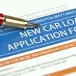 Fancy red pen on top of a blue, orange, and white car loan application form
