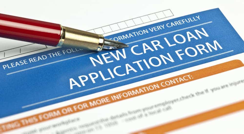 Fancy red pen on top of a blue, orange, and white car loan application form