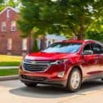 Red 2018 Chevrolet Equinox driving down a paved neighborhood street