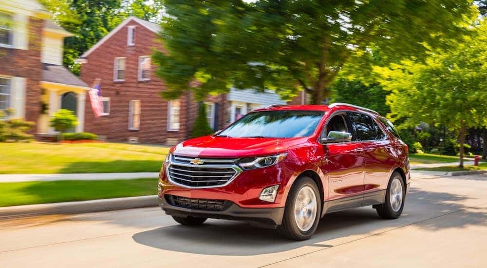 Red 2018 Chevrolet Equinox driving down a paved neighborhood street