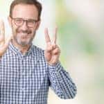 Man in a plaid shirt and glasses holding up seven fingers