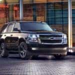 Midnight black 2017 Chevrolet Tahoe SUV parked on a black brick ground in front of an all glass building