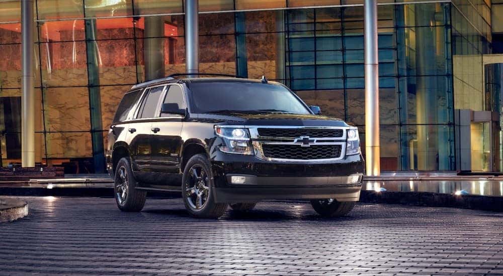 Midnight black 2017 Chevrolet Tahoe SUV parked on a black brick ground in front of an all glass building