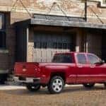 Red 2015 Chevrolet Silverado 1500 parked on a brick road next to a brick building