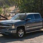 Dark-colored 2017 Chevrolet Silverado parked diagonally in front of a brown fence