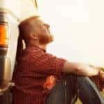 Person looking at the sky leaning against a vehicle