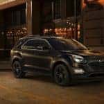 Black 2017 Chevrolet Equinox SUV parked on the side of the road next to a store front