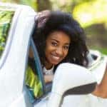 Young teen holding a car key and leaning out the side of a white convertible
