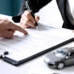 Woman in a suit signing a contract to buy a used car for sale