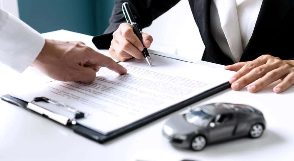 Woman in a suit signing a contract to buy a used car for sale