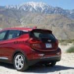 Red 2017 Bolt EV parked in dirt with mountains in the distance