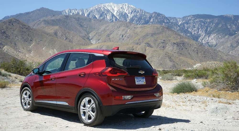 Red 2017 Bolt EV parked in dirt with mountains in the distance