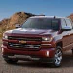 Red 2017 Chevrolet Silverado 1500 pickup truck parked across a paved road next to hills